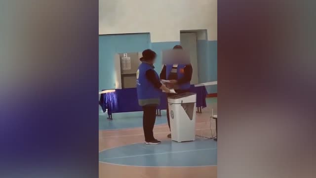 Электрондук урнага 2 адам дүңүнөн бюллетень салып жатат